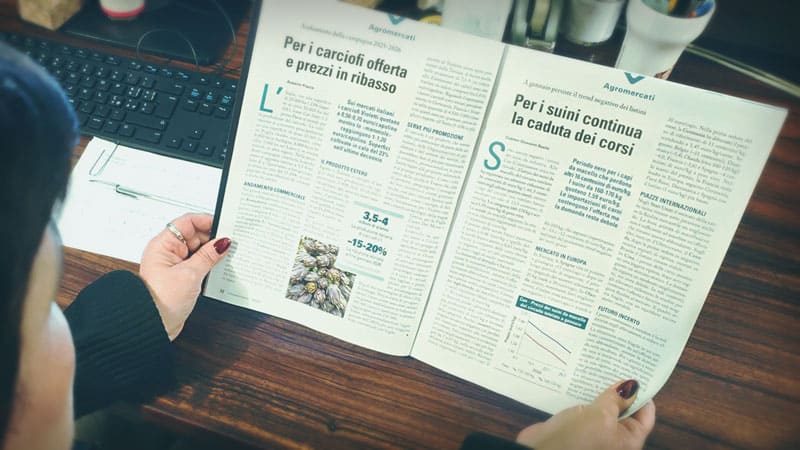 Questa immagine mostra una persona che legge una copia de L'Informatore Agrario